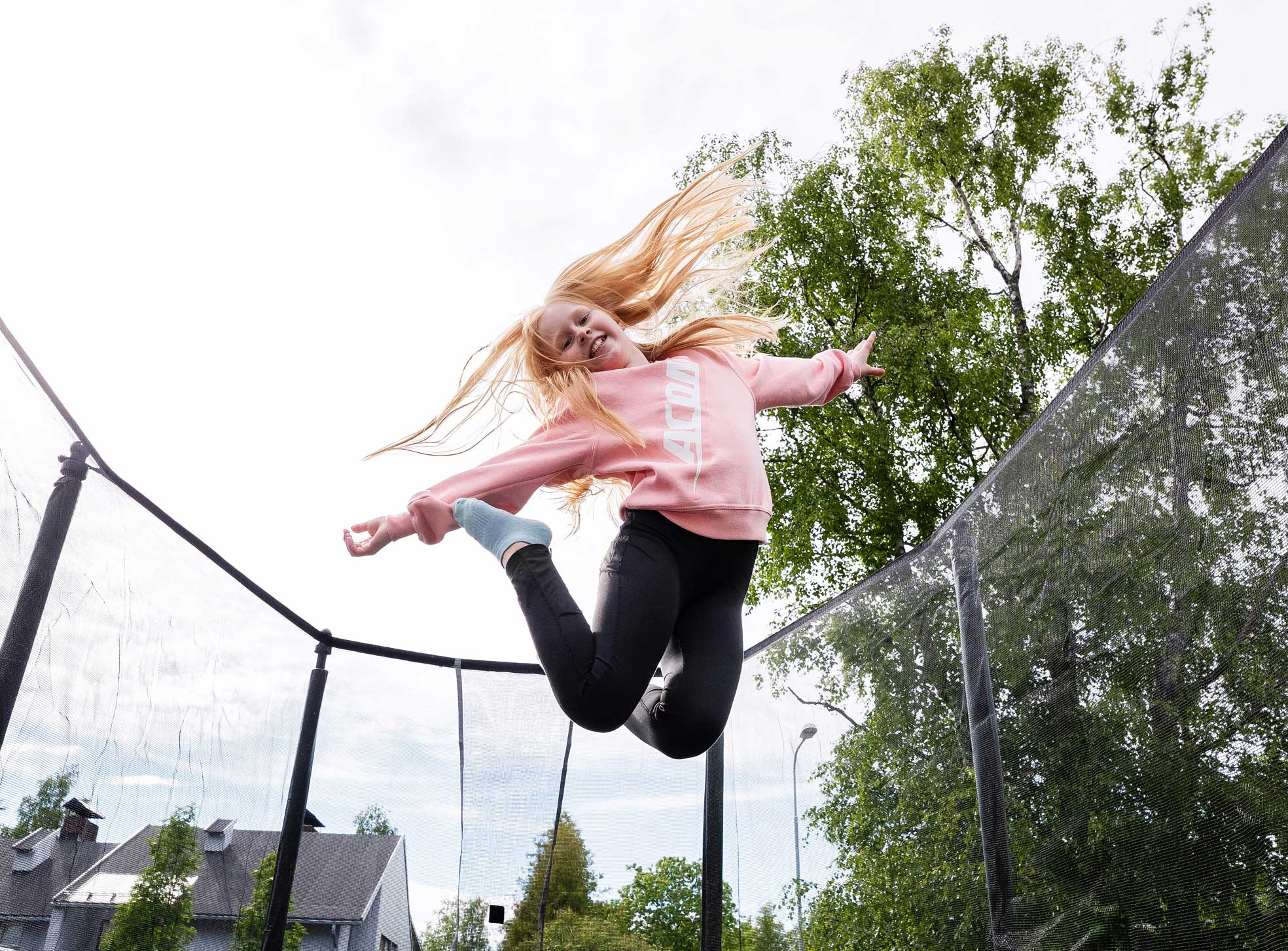 Girl wearing a pink Acon  sweater and jumps on Acon trampoline