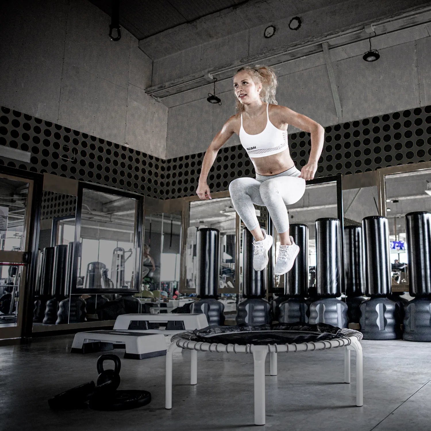 Athlete training on the ACON Fit 1,12m Round Rebounder Fitness Trampoline with Active Handlebar in a European gym.