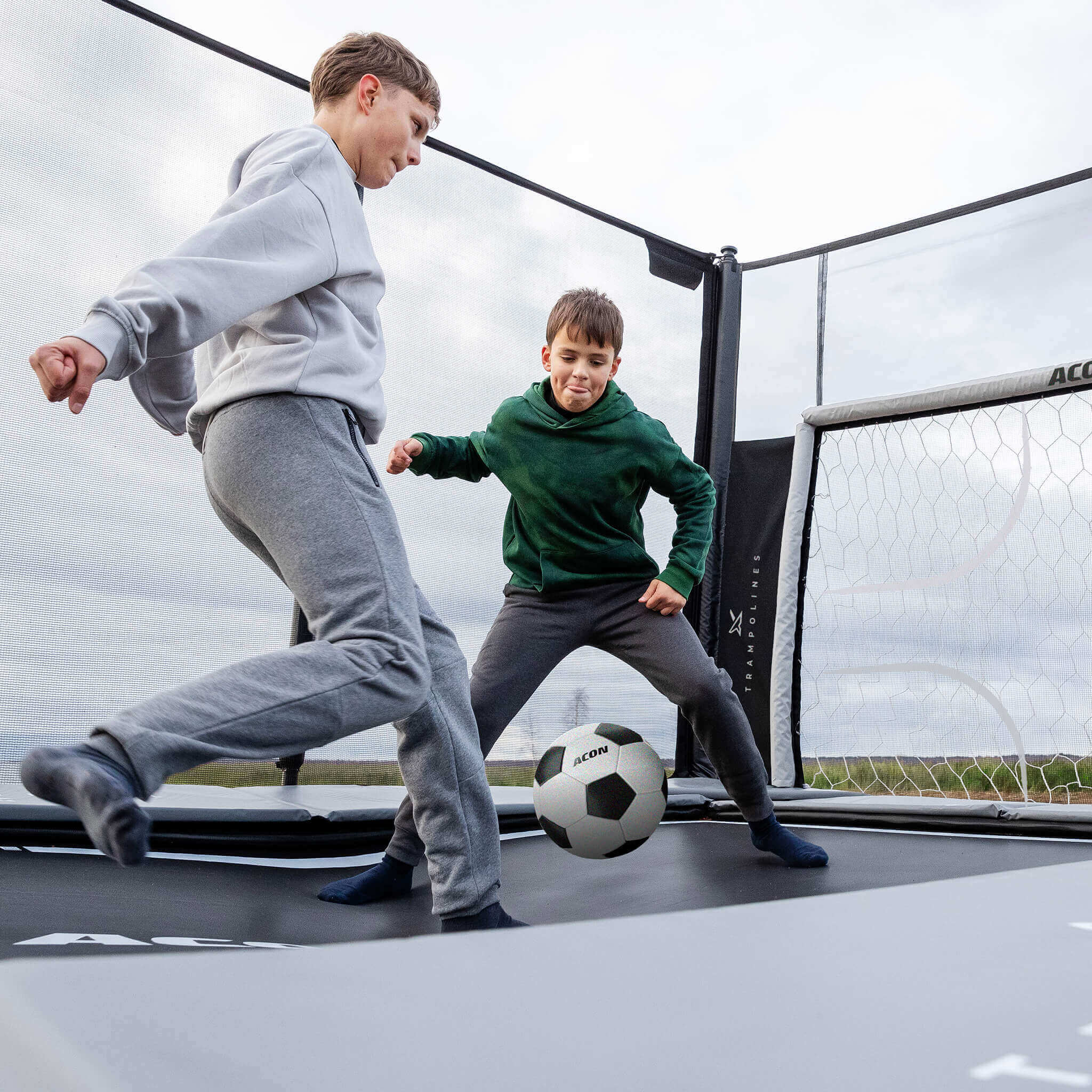 Two boys playing soccer on Acon X 17 Trampoline with soccer panel