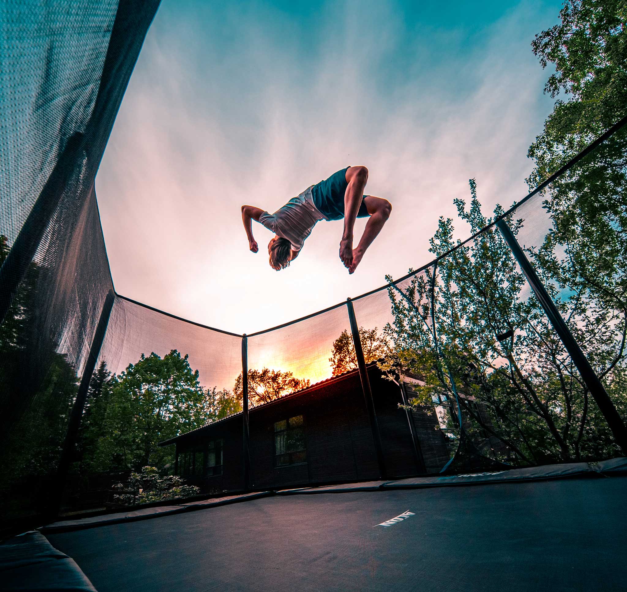 A boy doing a backflip on an ACON 16 Sport HD trampoline.