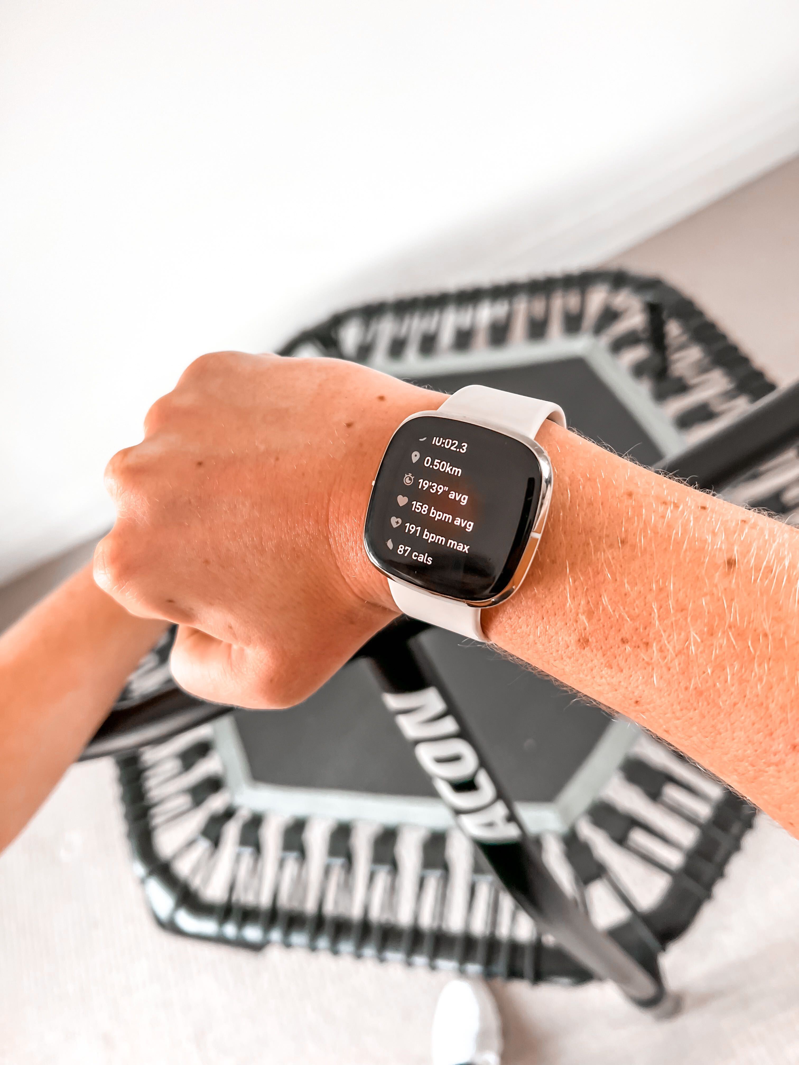 A closeup of a sports watch with an ACON rebounder trampoline in the background