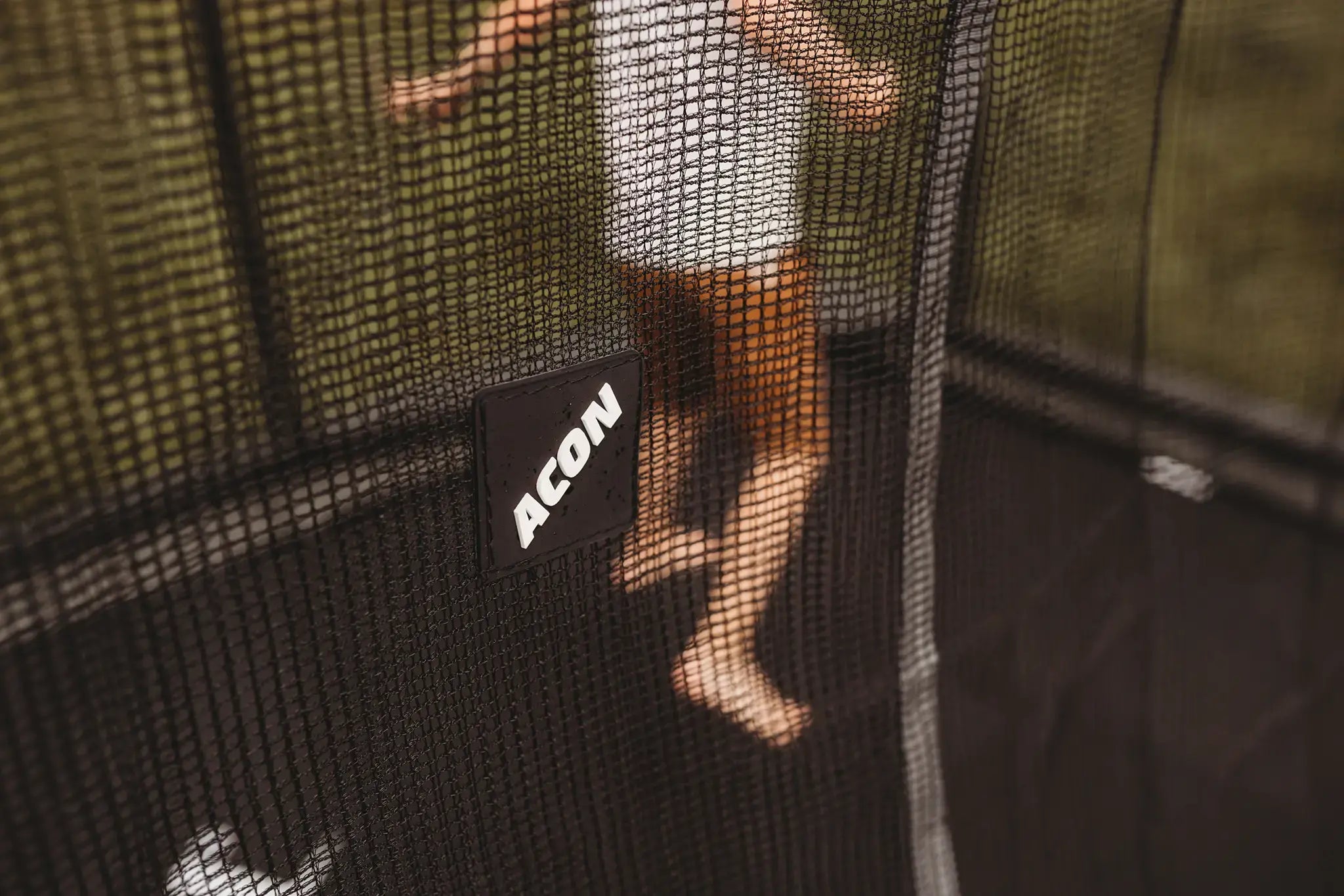 Child jumping on a Acon trampoline, seen trough safety net.