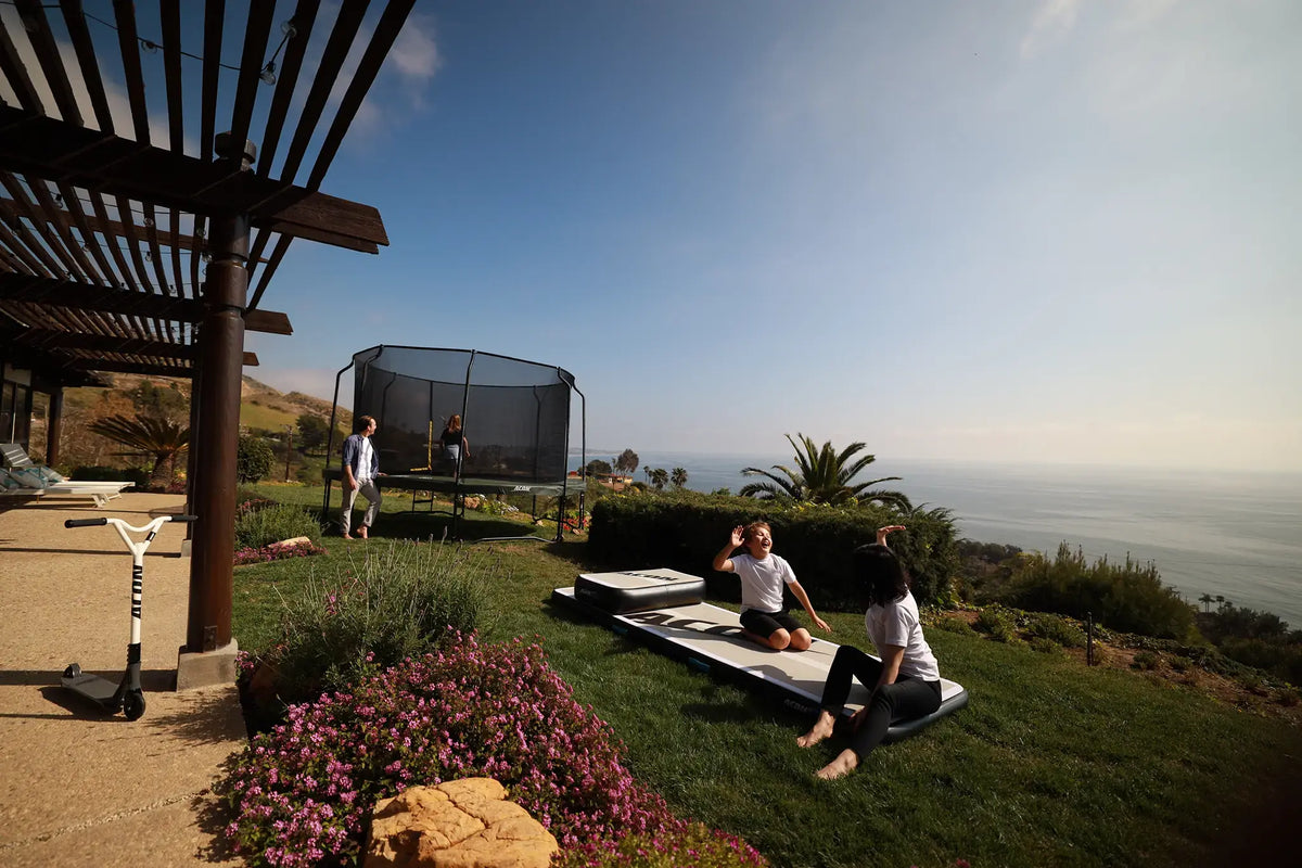 Family outside spending time together on a a sunny backyard, on the Acon airtrack and trampoline.