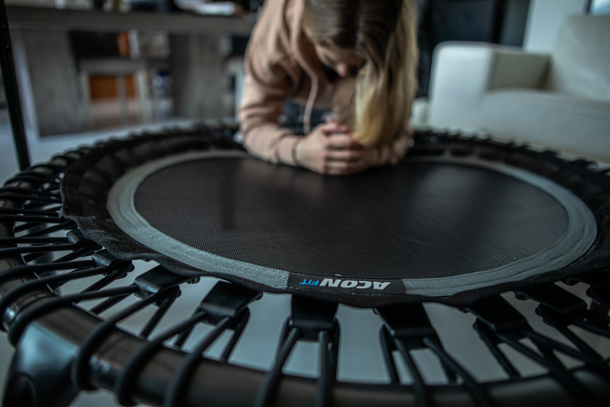 Indoor trampoline. A woman planking against the acon fitness trampoline.