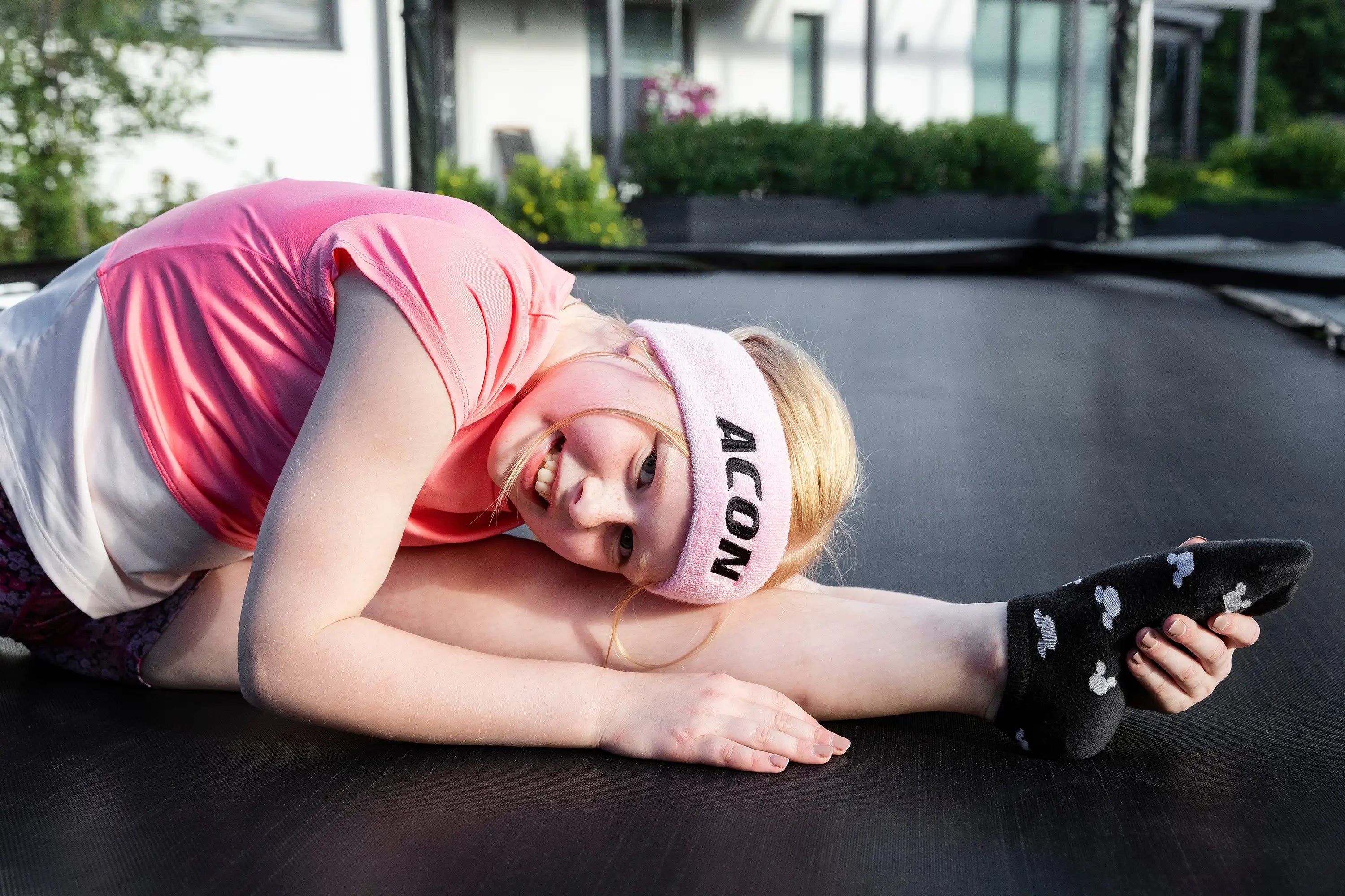 Close up image of a girl stretching on a trampoline.