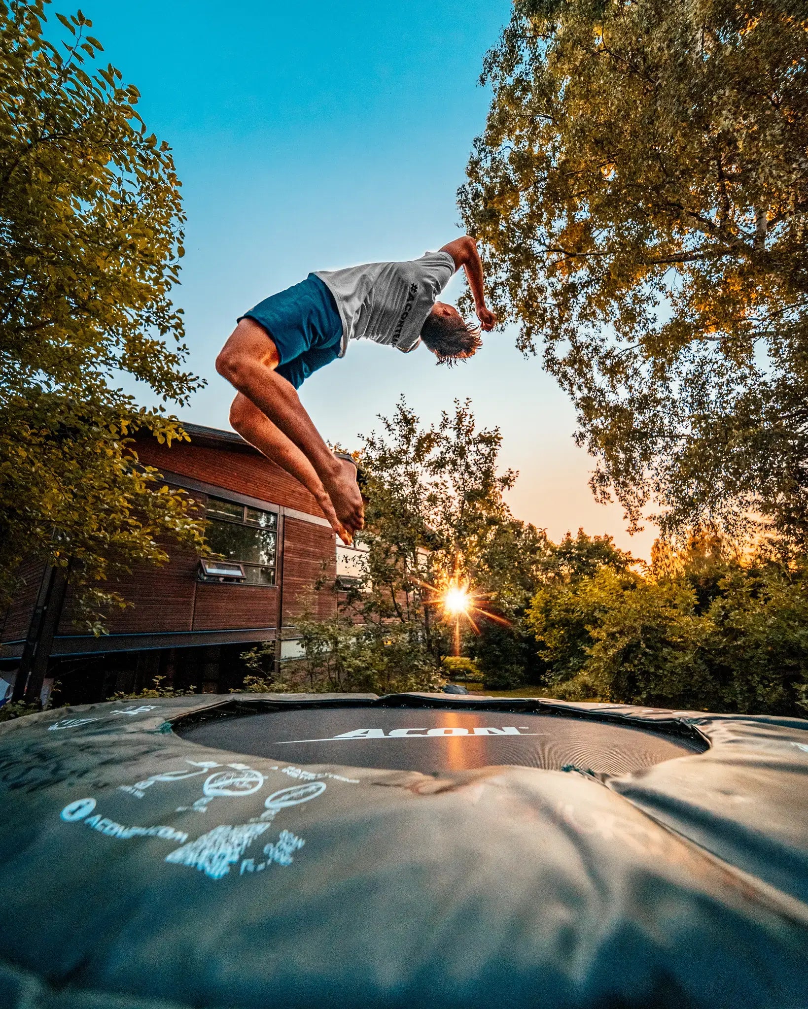 Boy doing a flip with a smaller round Acon trampoline. 