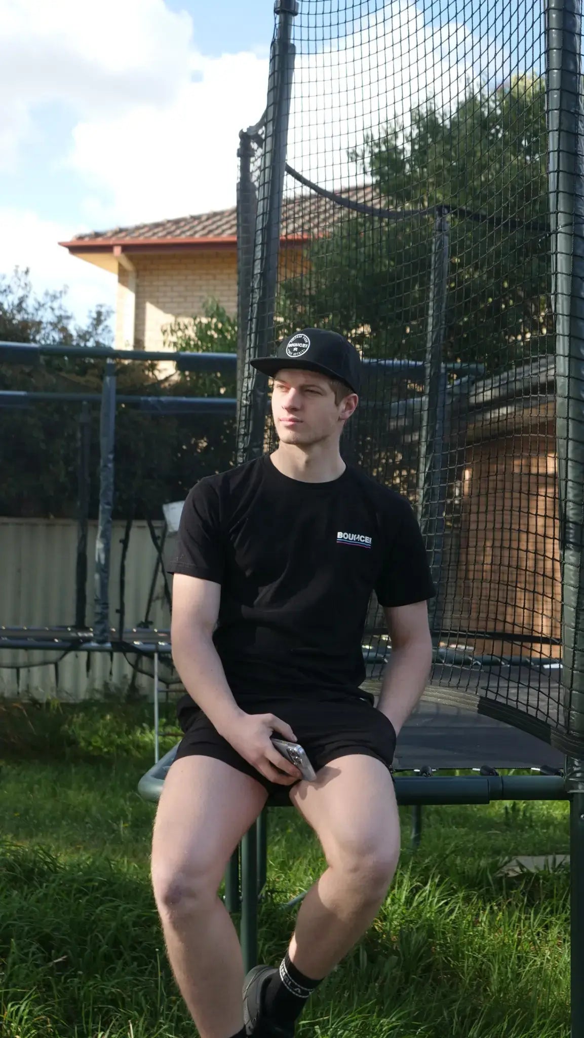 Trampoline athlete Alex Osborn sitting on a trampoline.