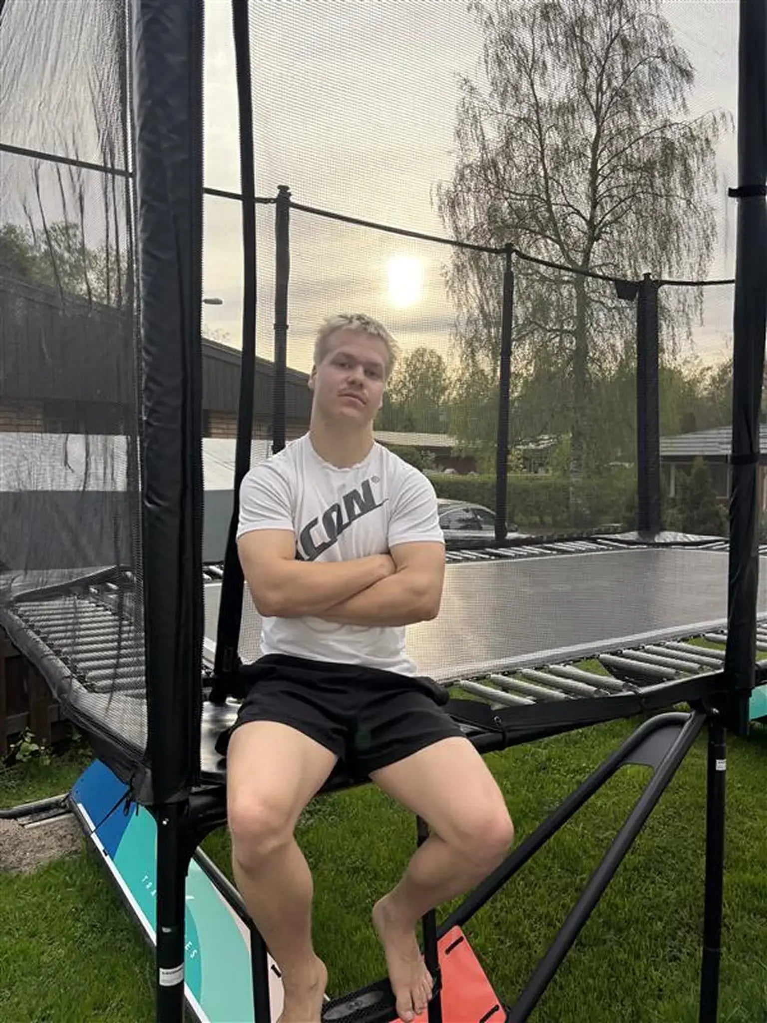 Trampoline athlete Leevi Valtonen sitting on the corner of a Acon trampoline. 