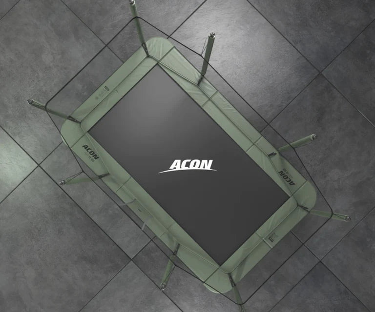 Acon HD rectangular trampoline from bird’s eye view on a grey background. The black trampoline mat has ACON logo on it in white and the paddings are green 