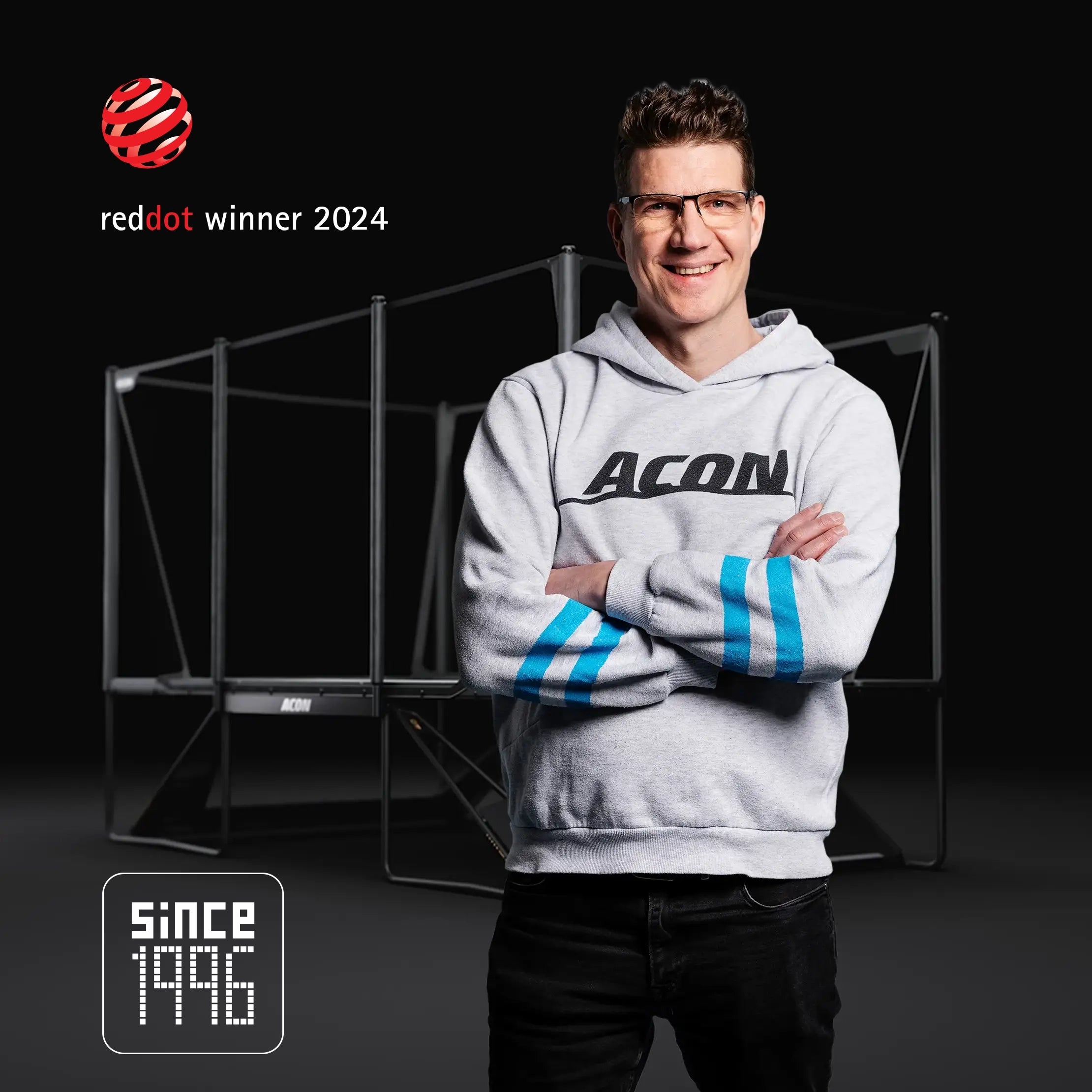 The founder of Acon, Tarmo Sallinen, standing in front of an X-trampoline. The image features the Red Dot Awarded 2024 emblem and the Since 1996 badge.