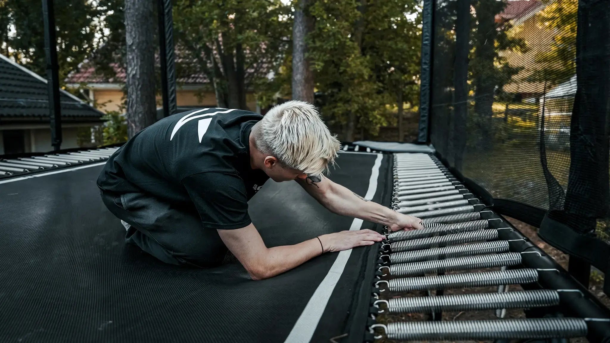 Blonde man adjusting Acon X trampoline springs.