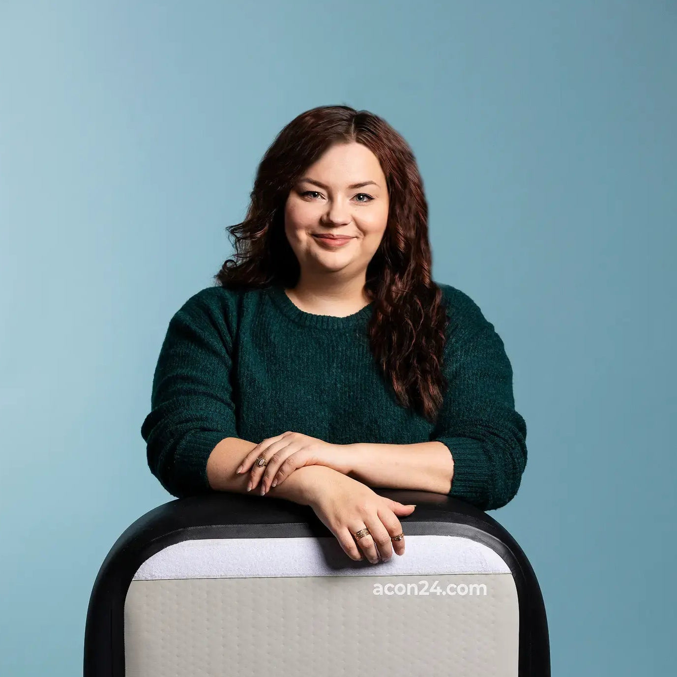 Janita Tuohino leaning her arms on an ACON airtrack against a light blue background.