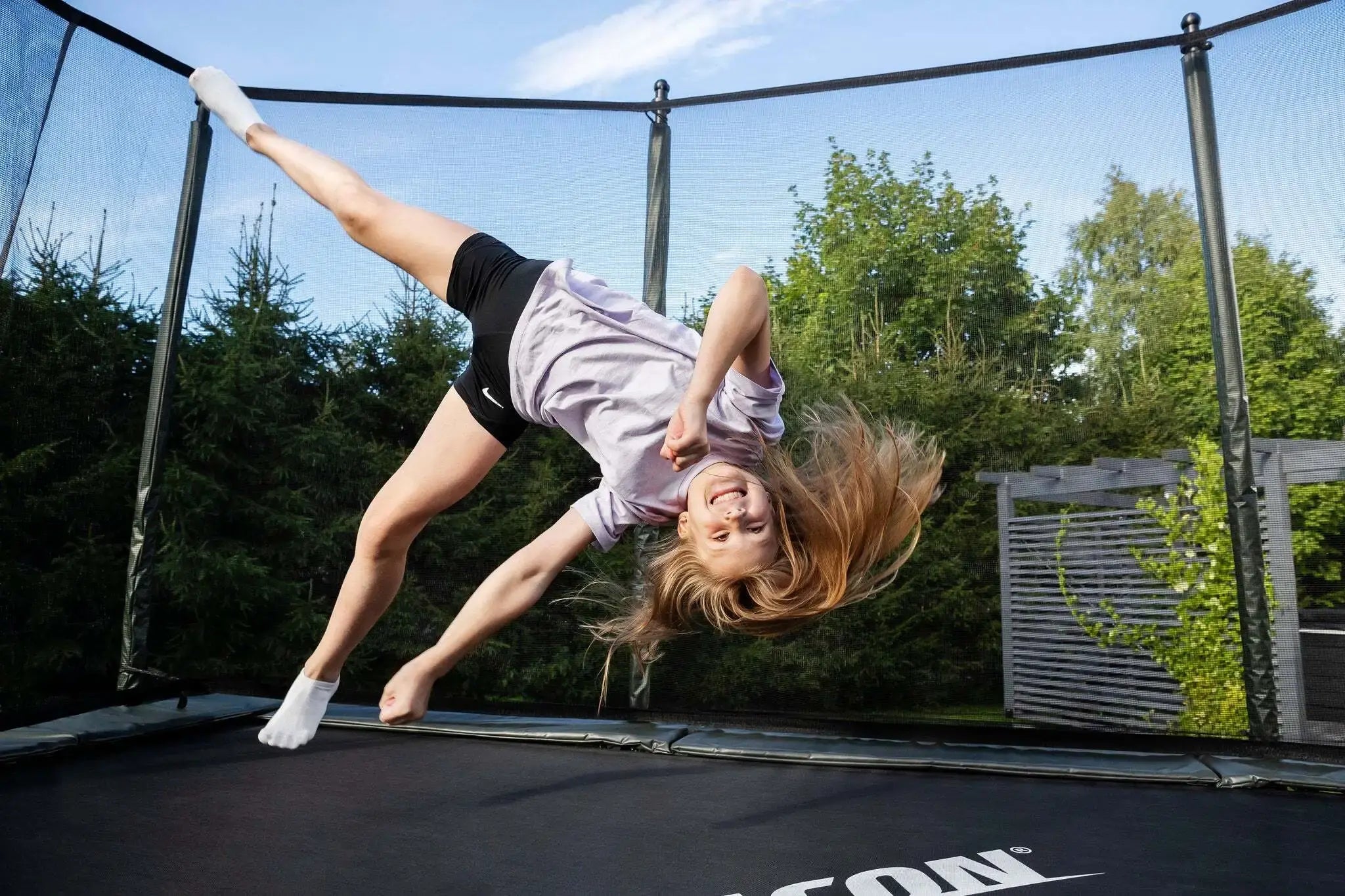 A girl doing a flying cartwheel on an Acon trampoline.