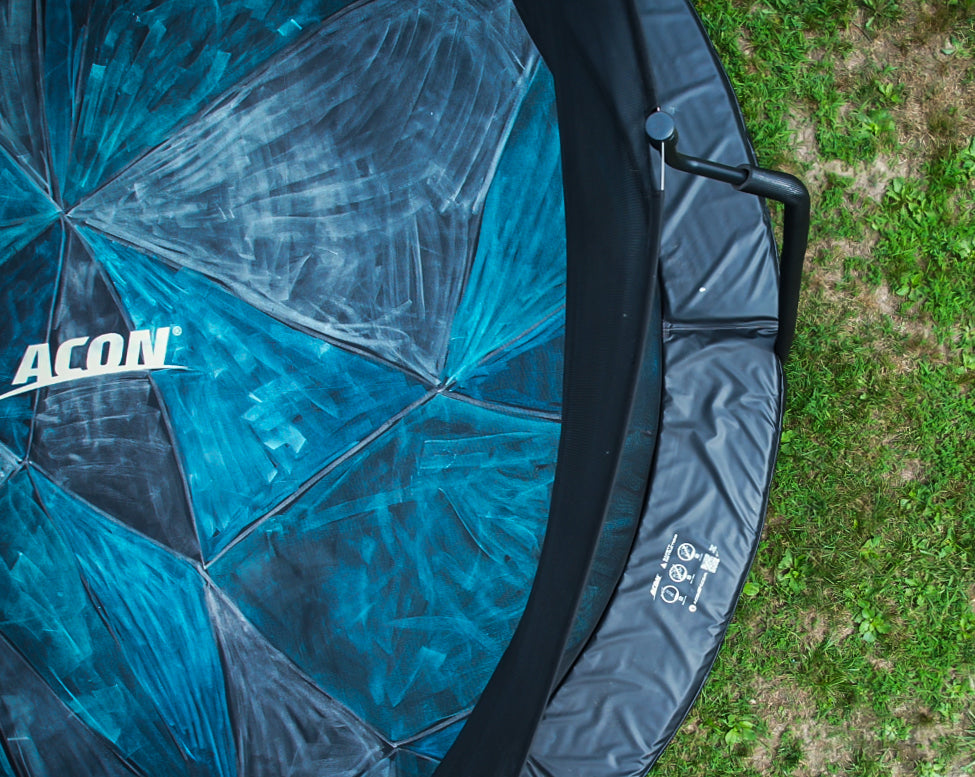 Detail of a trampoline with a mat colored with blue chalks, seen from above.