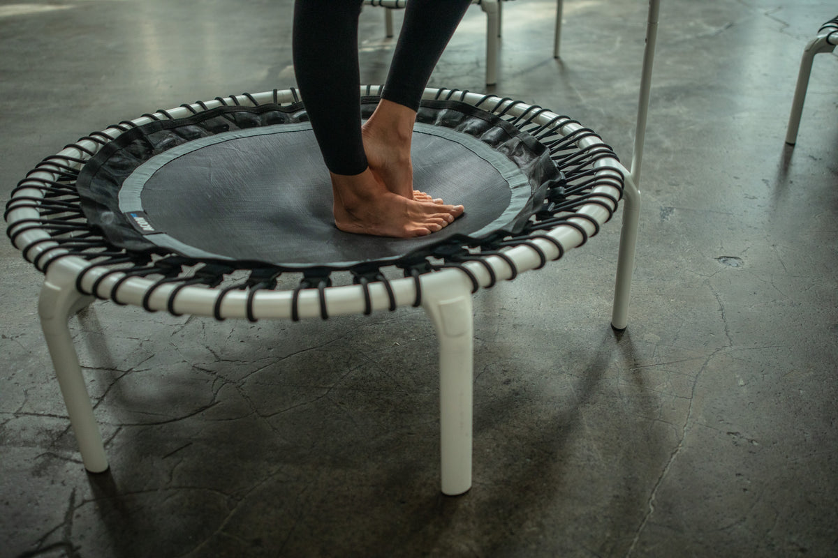 Close-up of a woman standing barefoot on a white round ACON rebounder.