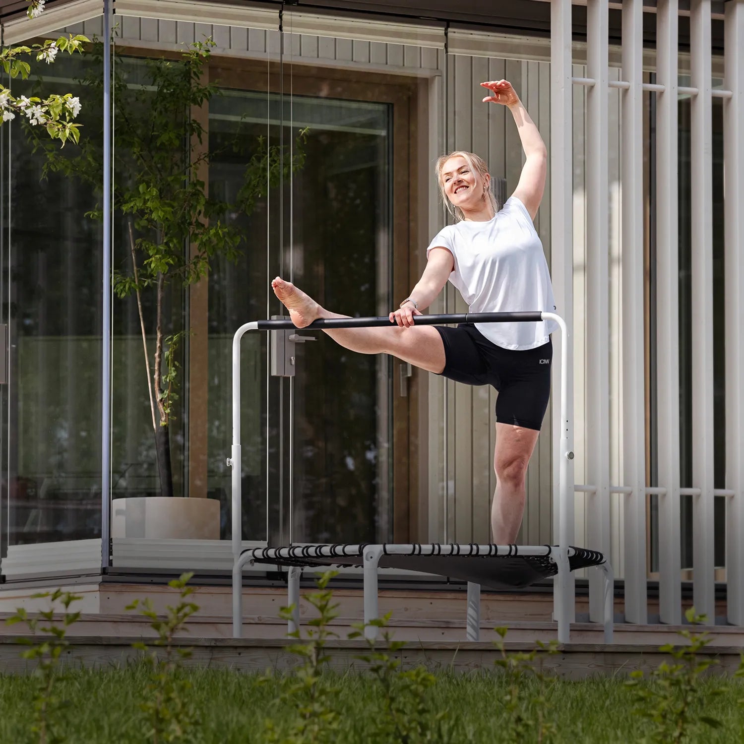 ACON Fit 1,12m Round Rebounder Fitness Trampoline with Balance Handlebar in outdoor use for stretching exercises.