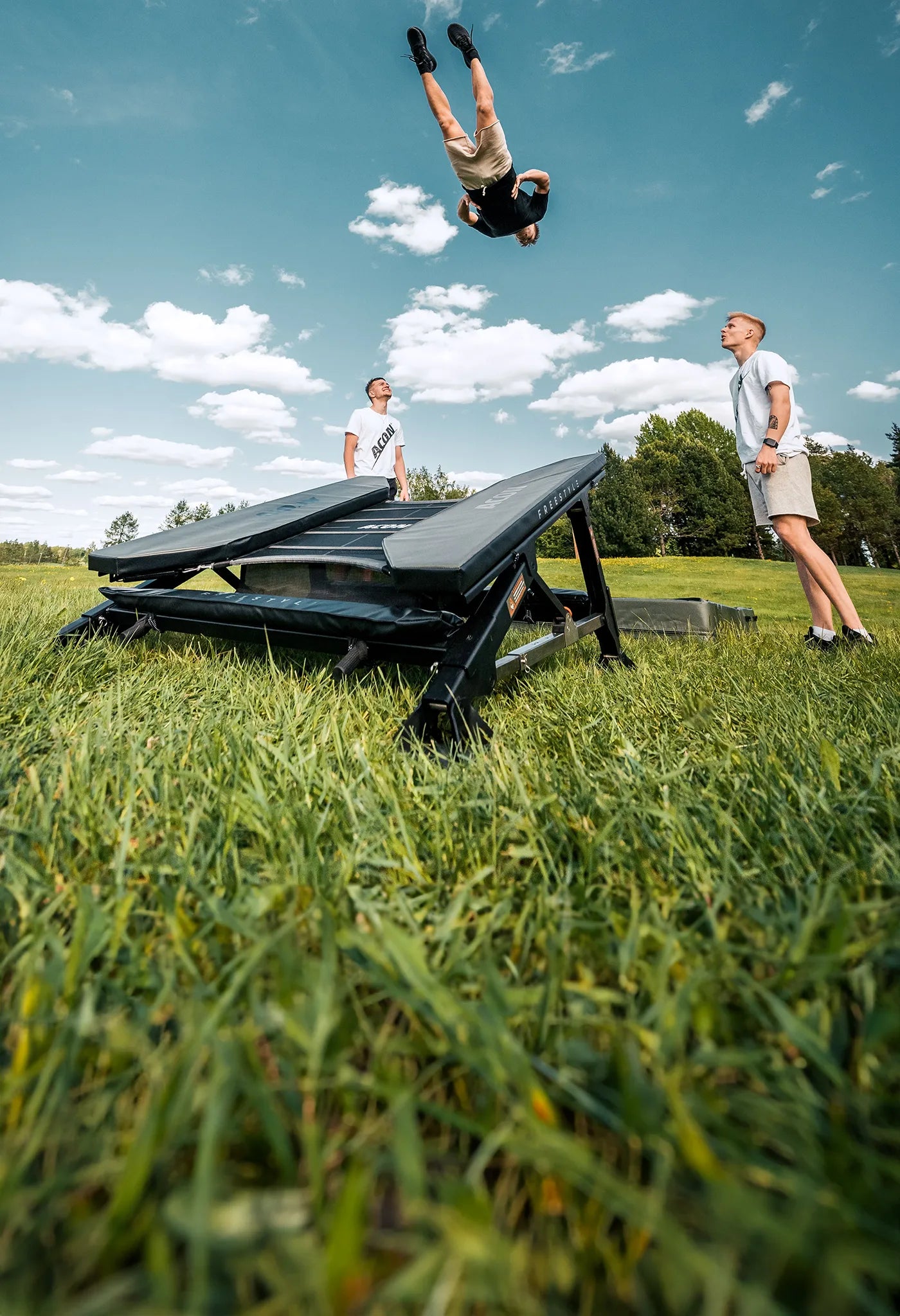 Acon Freestyle Mini trampoline outdoors and three trampoline trickers.