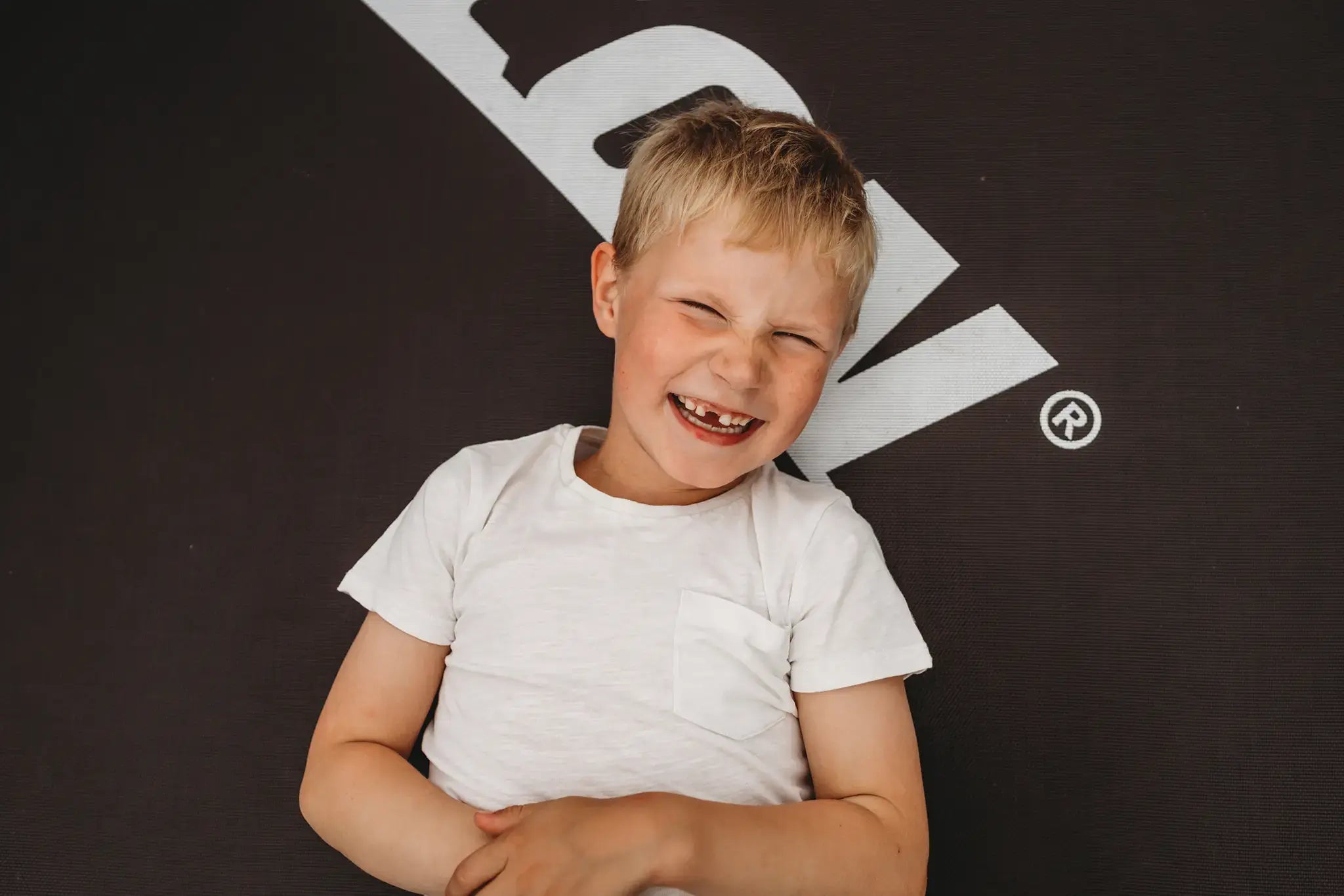 Happy boy smiling and laying on an Acon trampoline. 