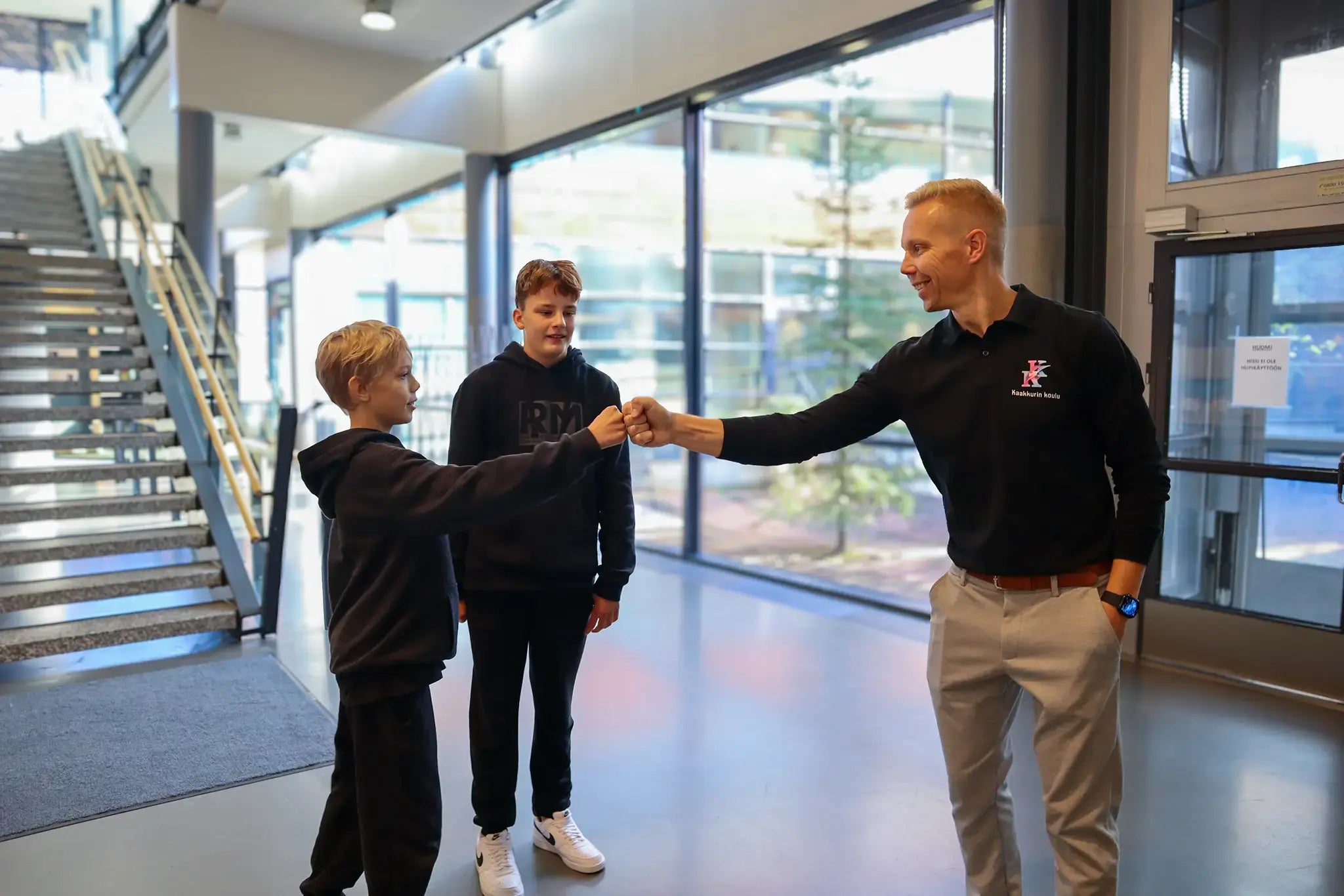 Two boys in Kaakkuri school shaking hands with the principal. 