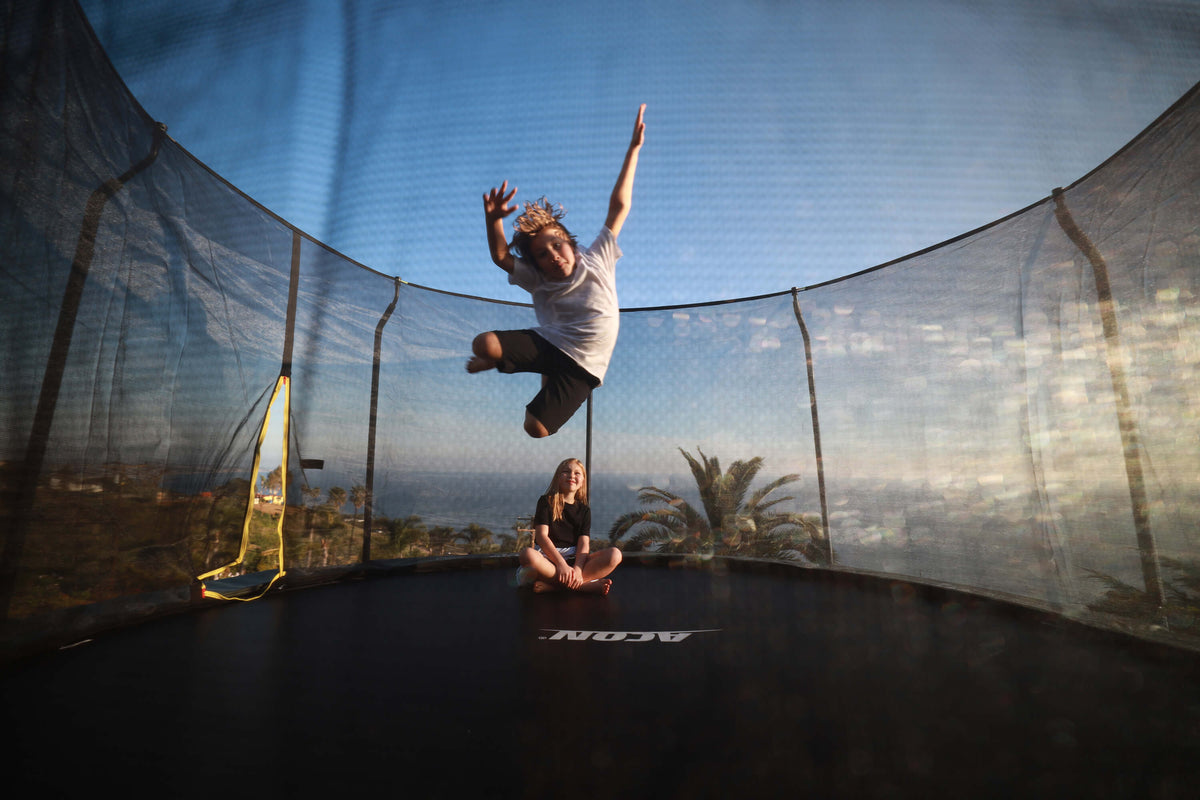 Children playing on a round ACON garden trampoline.