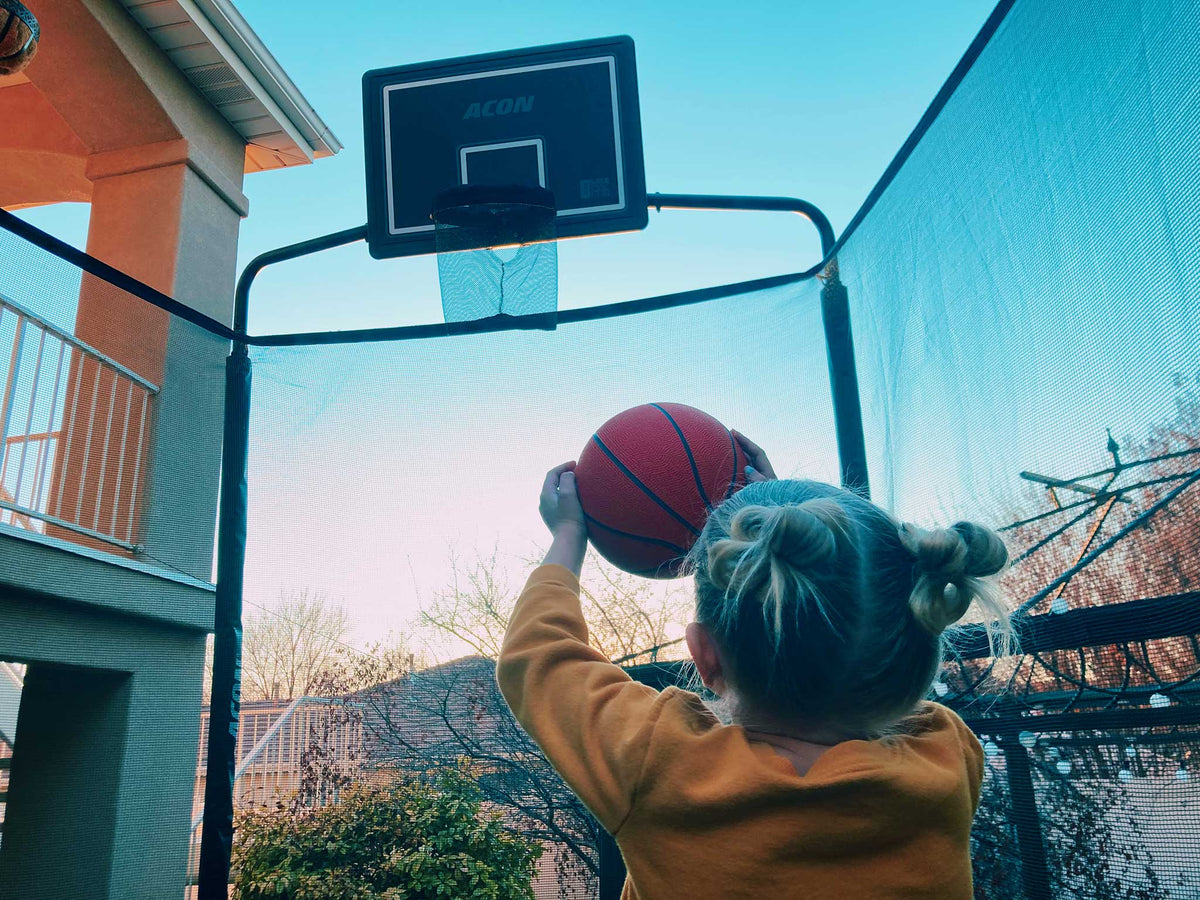 Little girl throwing a ball in to the Acon Trampoline Basketball hoop