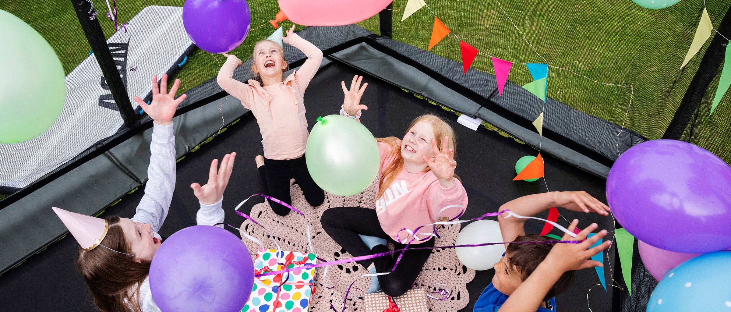 Four kids having a party on a decorated trampoline.