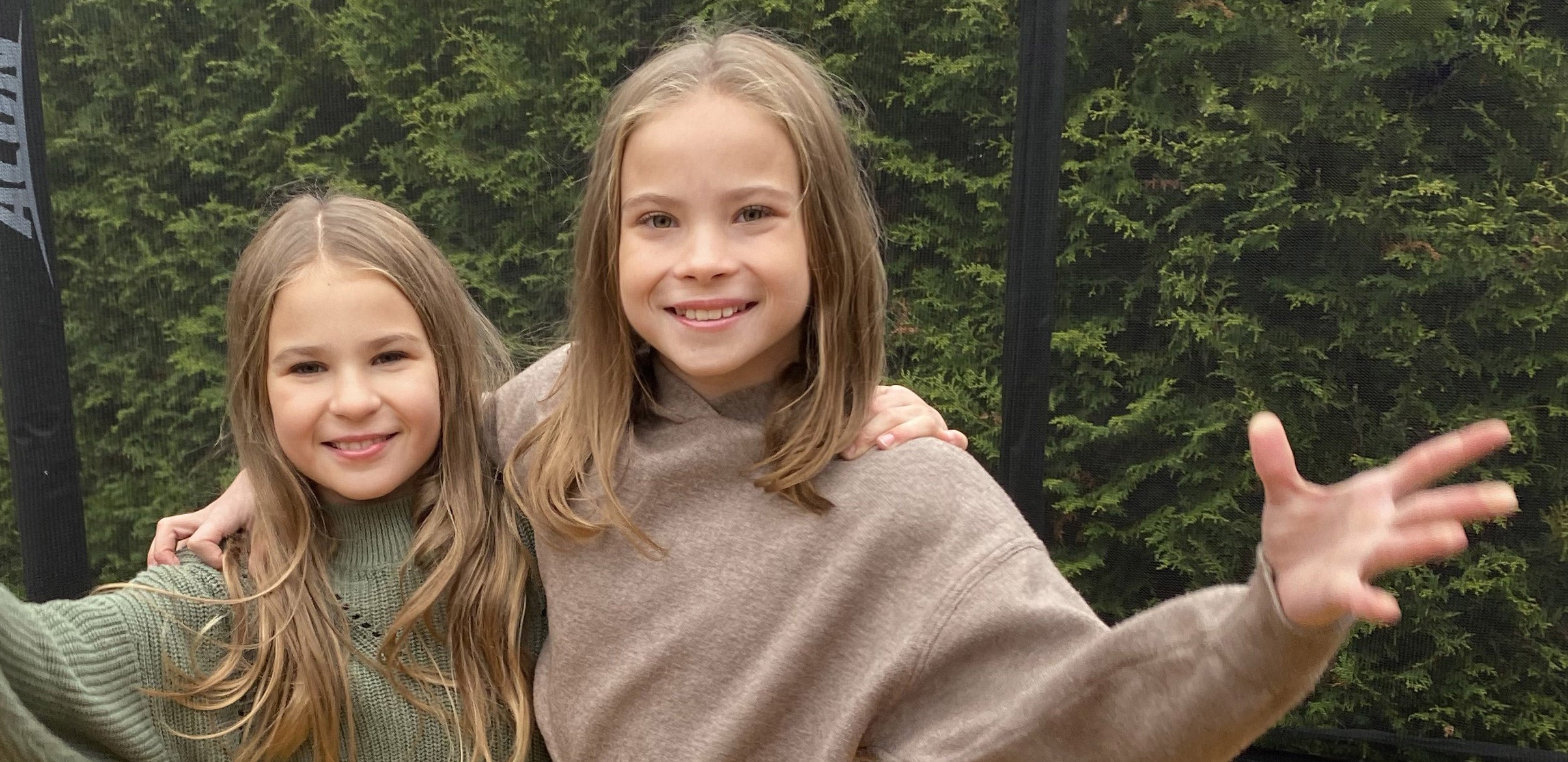 Two smiling girls on a trampoline.