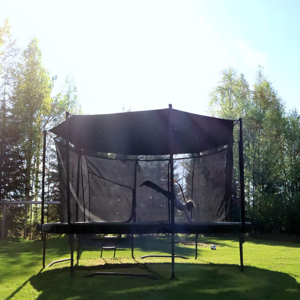 Acon Air round trampoline with a shade in a sunny outdoor setting, child jumping.