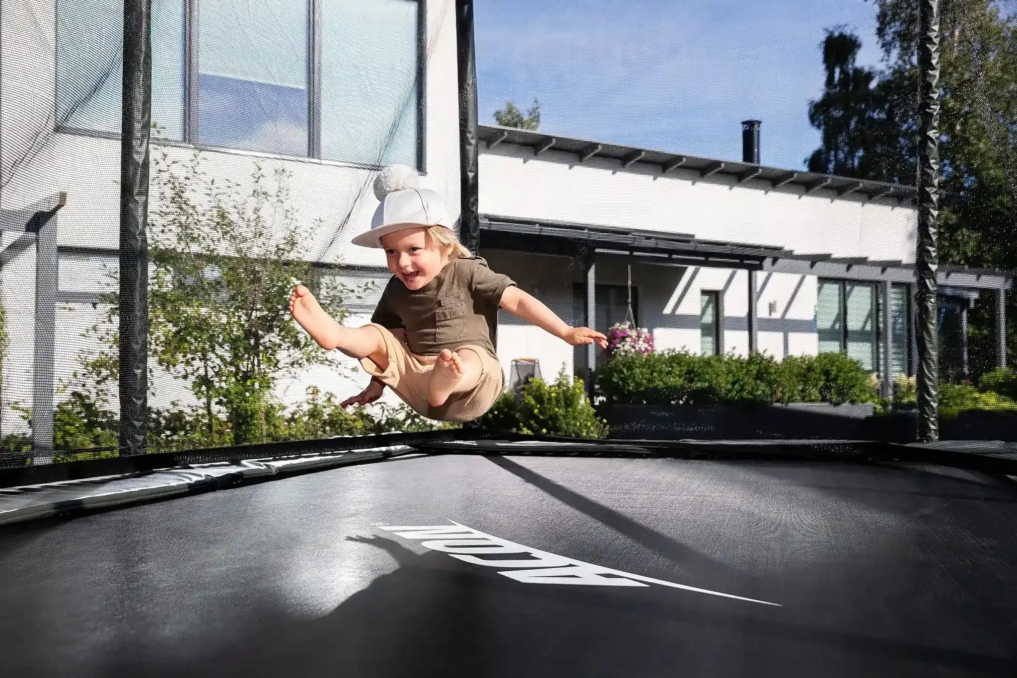 Toddler jumping on a rectangular Acon trampoline with safety net. 