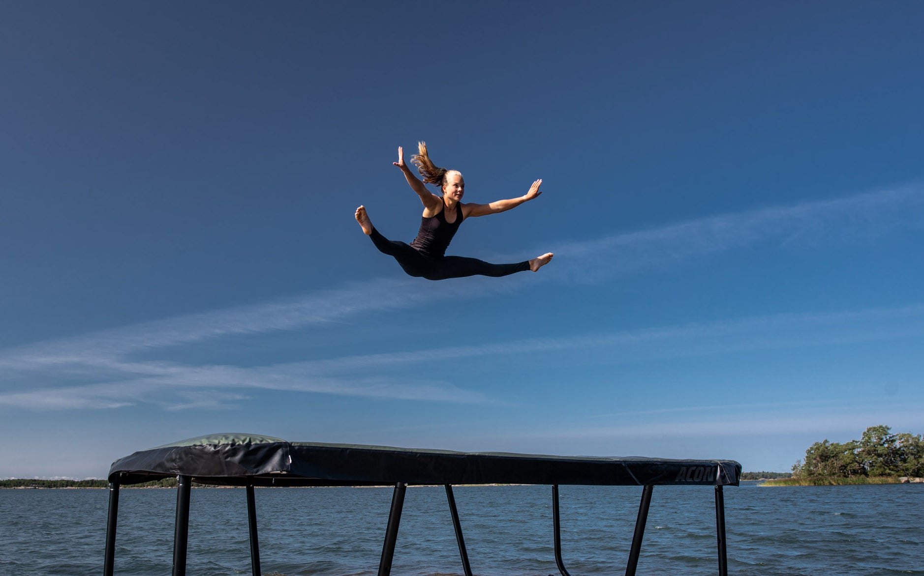 A woman jumps on Acon 13HD trampoline in an archipelago landscape