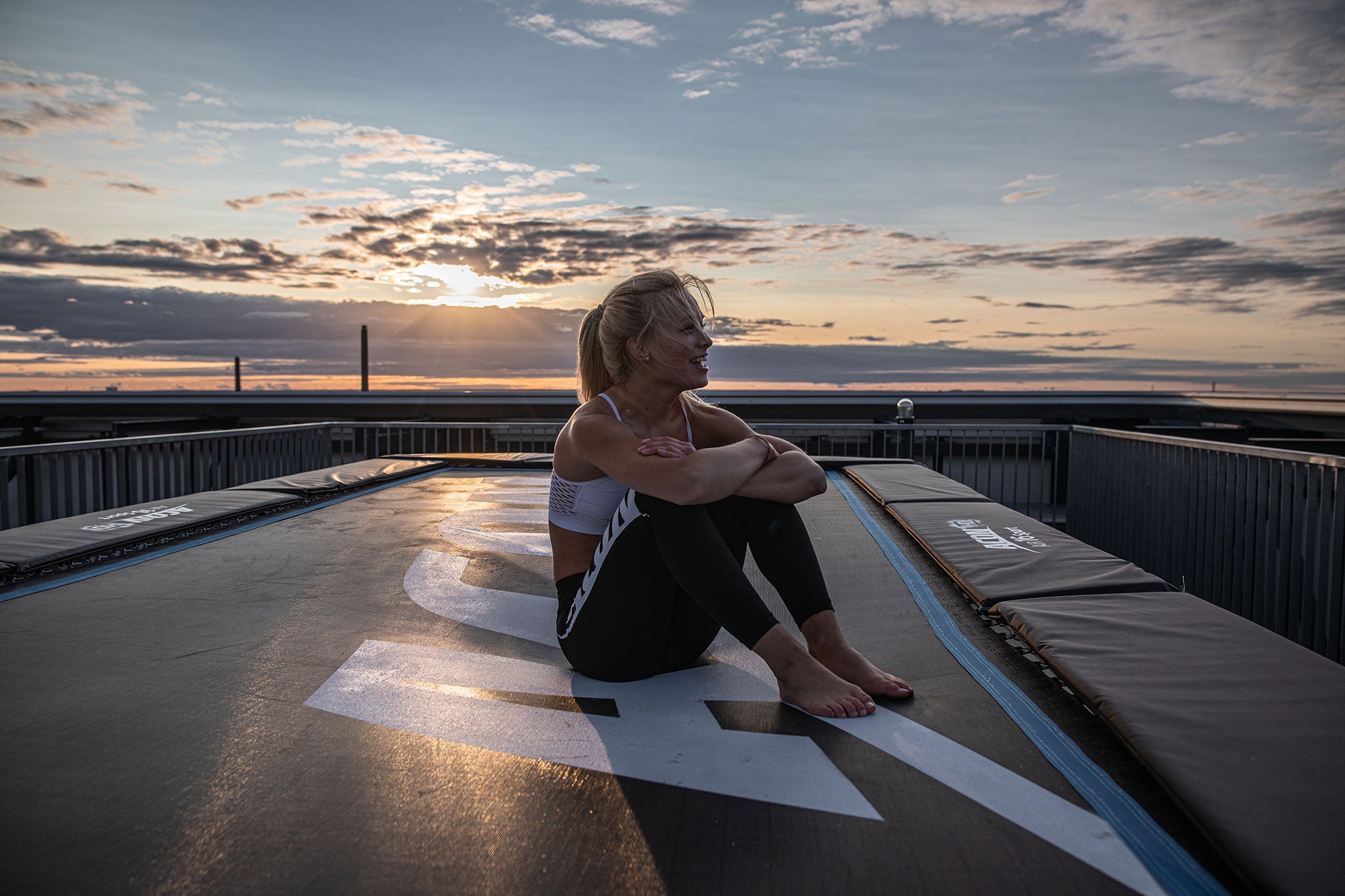 Cheerful woman sitting on an Acon 16 HD trampoline