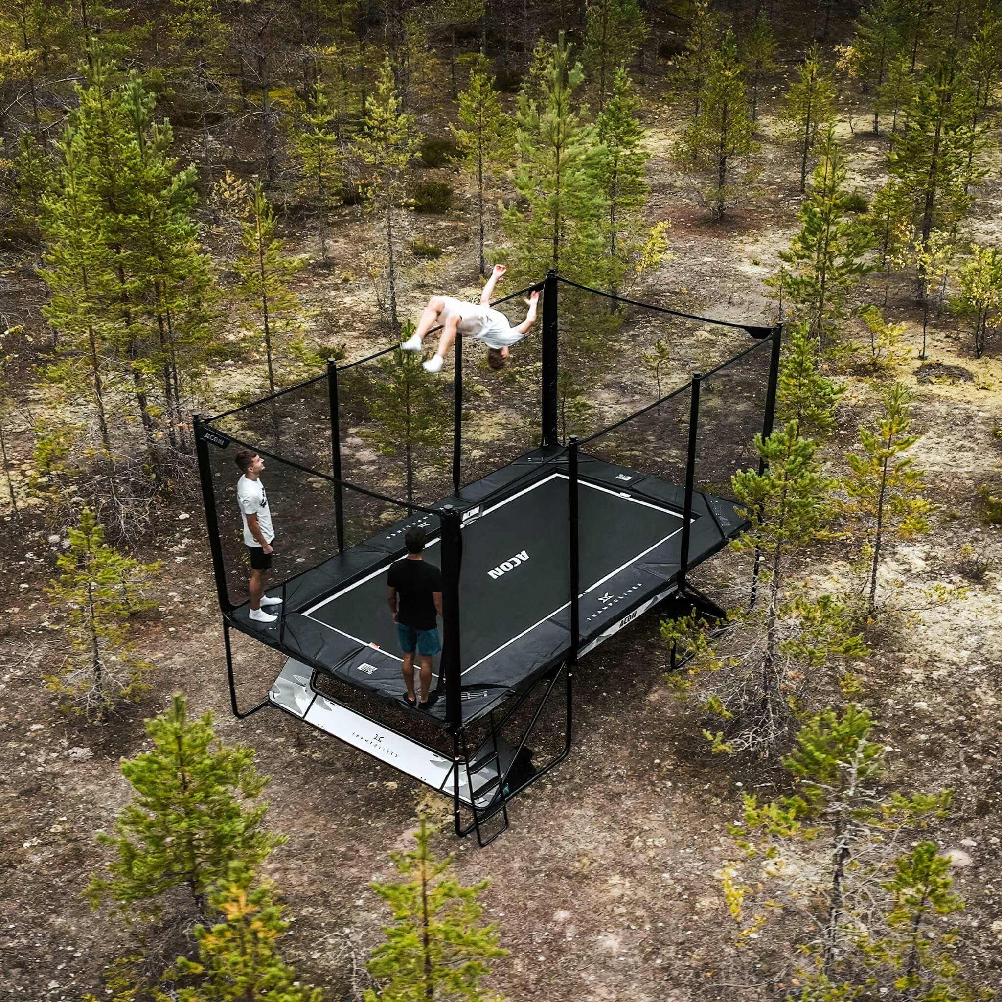 Three trampoline tricksters on an Acon X Trampoline in a Nordic pine forest.